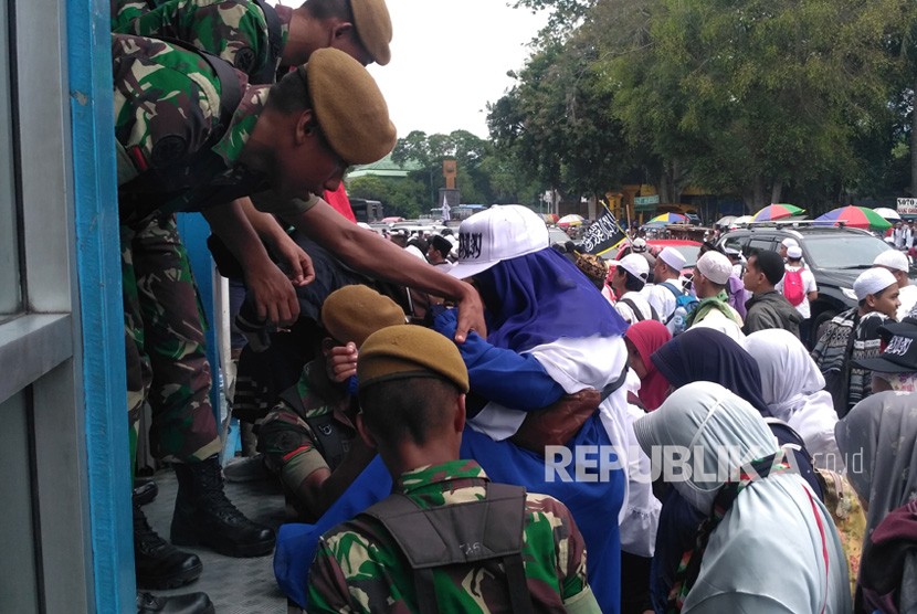 Anggota TNI membantu massa aksi Reuni 212 menyeberang jalan melewati halte Juanda, Ahad (2/12).