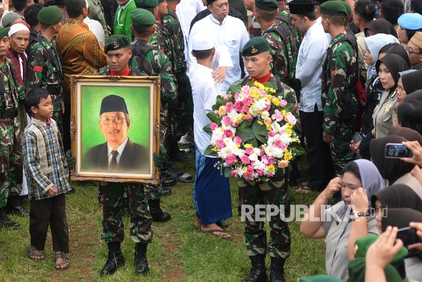 Anggota TNI membawa foto Almarhum KH. Hasyim Muzadi saat proses pemakaman di komplek Pondok Pesantren Al-Hikam, Depok, Jabar, Kamis (16/3).