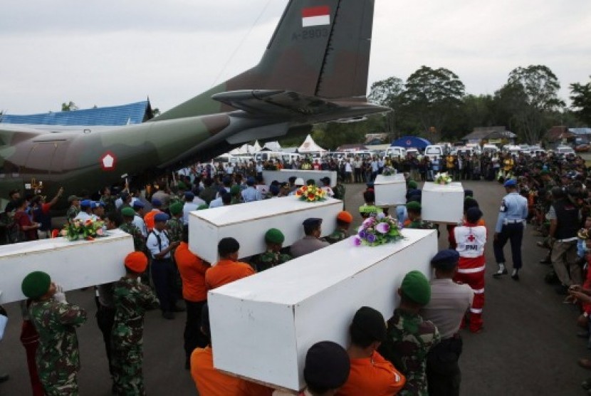 Anggota TNI membawa peti jenazah ke dalam pesawat untuk diterbangkan ke Surabaya.