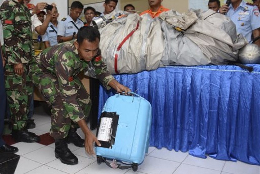  Anggota TNI memperlihatkan koper biru dan bagian pesawat yang ditemukan dari perairan tempat AirAsia QZ 8501 menghilang di Pangkalan Bun, Kalimantan. 