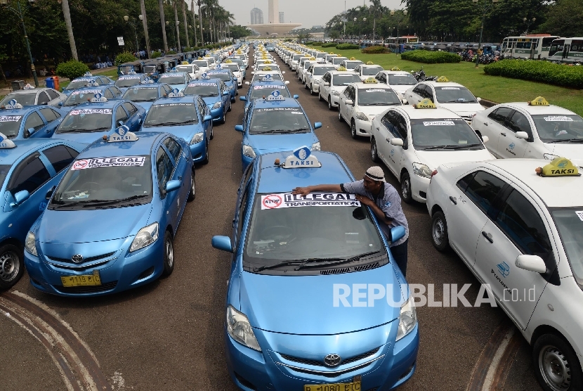 Angkutan umum diparkir di halaman Monas saat ribuan sopir melakukan aksi di depan Balai Kota DKI Jakarta, Senin (14/3).