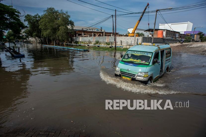 Angkutan umum melintasi banjir rob di kawasan Pelabuhan Perikanan Samudera Nizam Zachman, Muara Baru, Jakarta, Sabtu (6/11/2021). Badan Penanggulangan Bencana Daerah (BPBD) DKI Jakarta memperkirakan puncak musim hujan dan potensi rob di Ibu Kota terjadi pada Januari hingga Februari 2022. 