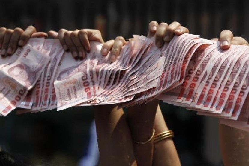 Anti-government protesters hold Thai baht banknotes to donate to protest leader Suthep Thaugsuban (unseen) as he leads a march through central Bangkok March 28, 2014.