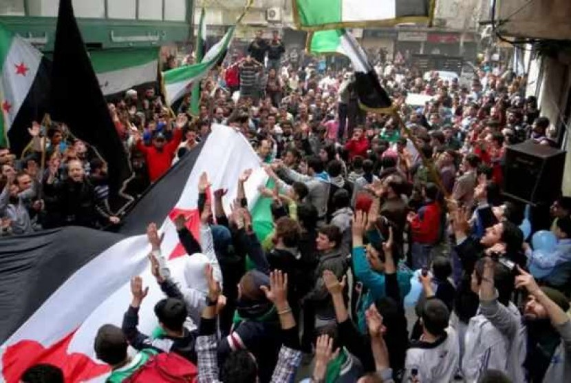 Anti-Syrian regime protesters raise up their hands as they wave Syrian revolutionary flags during a protest to mark the second anniversary of the their uprising, in Aleppo, Syria, Friday March 15, 2013.