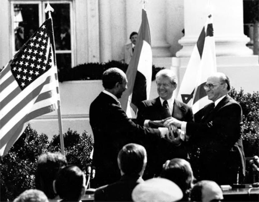 Anwar El Sadat (Presiden Mesir), Jimmy Carter (Presiden AS) Menachem Begin (Perdana Menteri Israel) berjabat tangan dalam perjanjian Camp David.