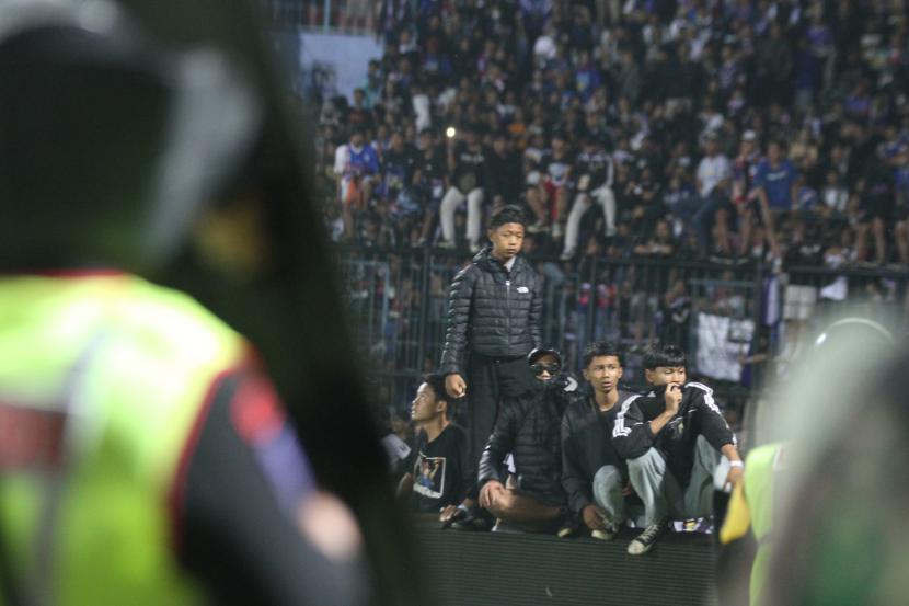 Aparat keamanan berusaha menghalau suporter yang masuk ke lapangan usai pertandingan BRI Liga 1 antara Arema melawan Persebaya di Stadion Kanjuruhan, Malang, Jawa Timur, Sabtu malam (1/10/2022). Polda Jatim mencatat jumlah korban jiwa dalam kerusuhan tersebut sementara sebanyak 127 orang.