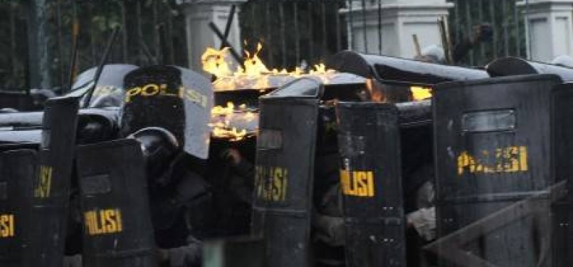 Aparat kepolisian berlindung dari lemparan molotov saat terjadi bentrok antara pengunjuk rasa dengan polisi di kawasan Gambir, Jakarta, Selasa (27/3). 