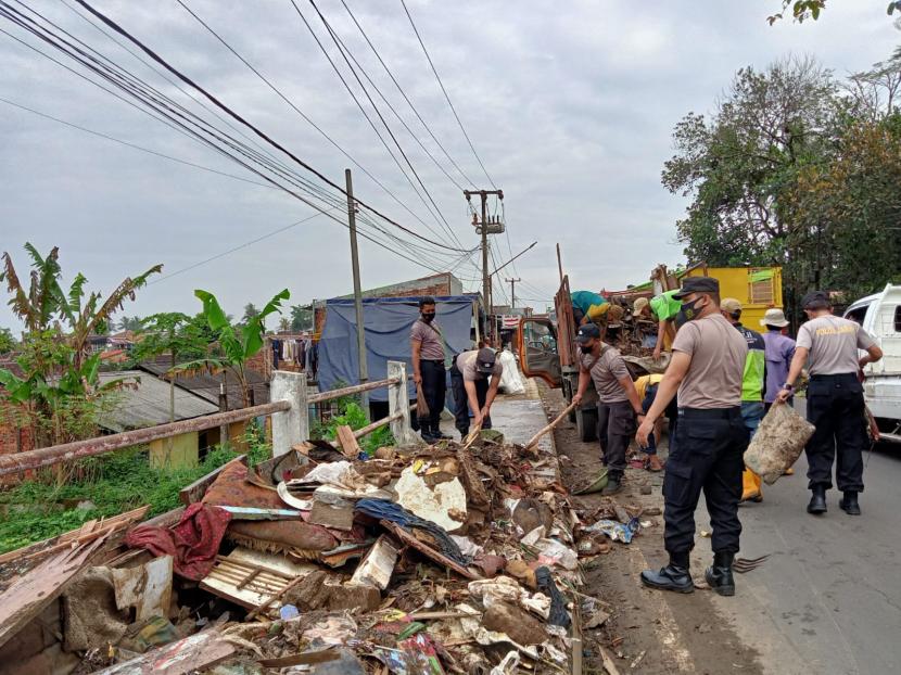 Aparat kepolisian dan petugas kebersihan Dinas Lingkungan Hidup (DLH) Kota Sukabumi mengangkut material dampak banjir di Kecamatan Baros, Kota Sukabumi, Senin (21/2/2022).