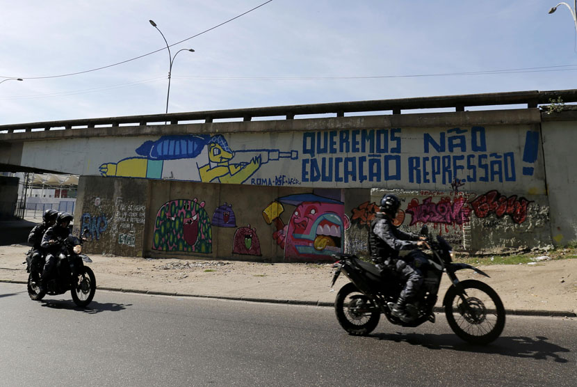  Aparat kepolisian melewati sebuah grafiti maskot Piala Dunia 2014, Fuleco, di salah satu sudut kota Rio de Janeiro. 