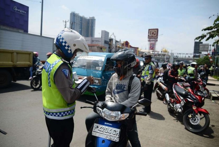  Aparat kepolisian memeriksa kelengkapan surat kendaraan pengendara motor saat menggelar operasi Zebra Jaya 2014 di Jalan Margonda Raya, Depok, Jumat (28/11).    (Republika/Raisan Al Farisi)