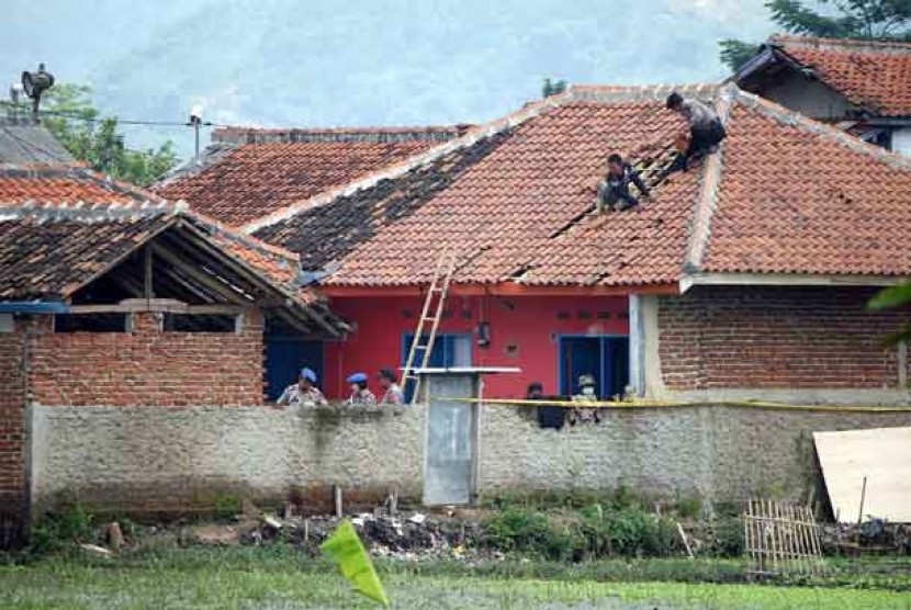   Aparat Kepolisian memperbaiki kerusakaan di rumah lokasi penangkapan teroris di Cigondewah Hilir, Marga Asih, Kabupaten Bandung, Kamis (9/5).