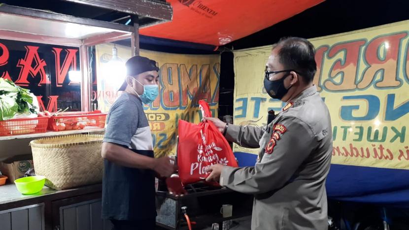 Aparat Polres Sukabumi Kota membagikan sembako ke pedagang sambil patroli PPKM darurat di Jalan Ahmad Yani, Kota Sukabumi, Kamis (15/7) malam