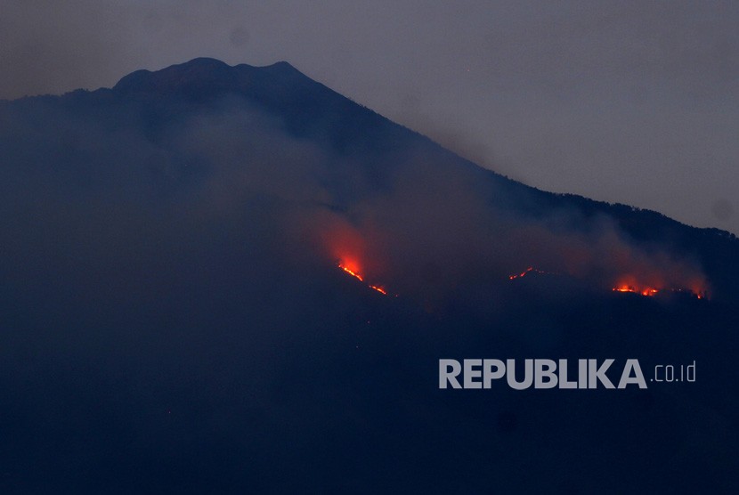 Api membakar hutan di lereng Gunung Arjuno terlihat dari Desa Landungsari, Malang, Jawa Timur, Jumat (11/10/2019).