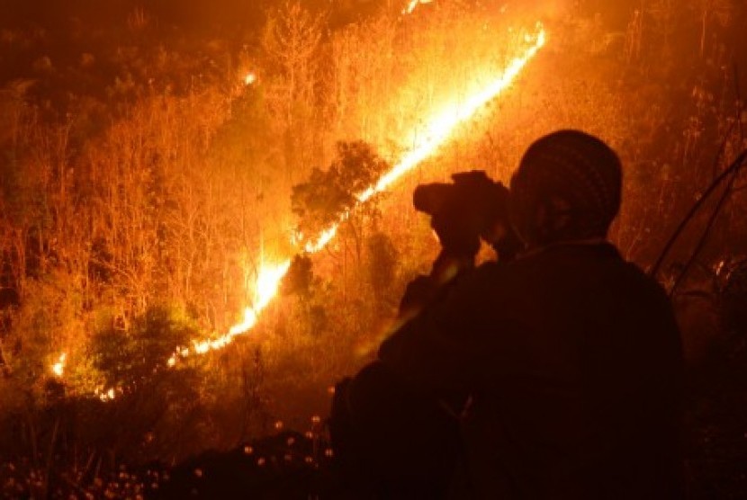 Api membakar kawasan hutan di lereng Gunung Wilis terlihat dari Desa Kresek, Wungu, Madiun, Jumat (23/10) malam. 