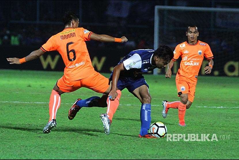 Gelandang Arema FC Hamka Hamzah (tengah) berusaha melewati hadangan pesepak bola Persija Jakarta Maman Abdurahman (kiri) dan Riko Simanjuntak (kanan) dalam pertandingan Liga I di Stadion Kanjuruhan, Malang, Jawa Timur, Minggu (5/8).