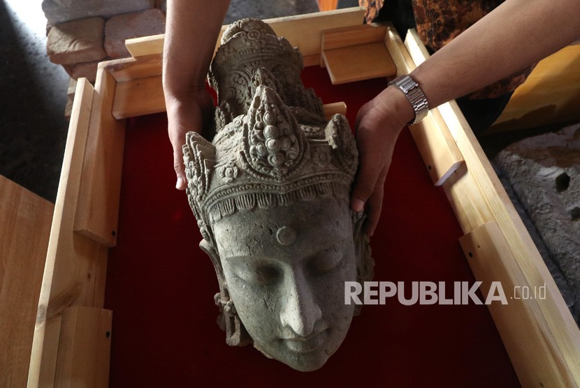 Arkeolog Dinas Kebudayaan dan Pariwisata memasukkan potongan kepala arca Bodhisatwa yang baru saja ditemukan ke dalam kotak kaca di Museum Bhagawanta Bari, Kediri, Jawa Timur, Rabu (17/7/2019). 