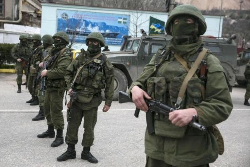 Armed servicemen stand near Russian army vehicles outside a Ukrainian border guard post in the Crimean town of Balaclava March 1, 2014.