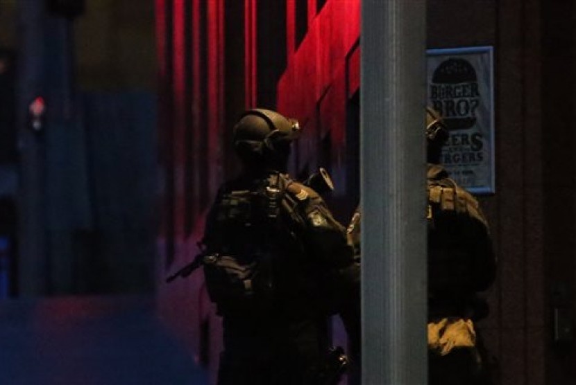 Armed tactical response police personnel stand watch into the evening near a cafe under siege by a gunman at Martin Place in the central business district of Sydney, Australia, Monday, Dec. 15, 2014.