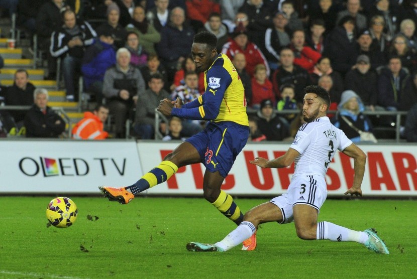 Arsenal's Danny Welbeck (L) shoots past Swansea City's Neil Taylor during their English Premier League soccer match at the Liberty Stadium in Swansea, Wales November 9, 2014.