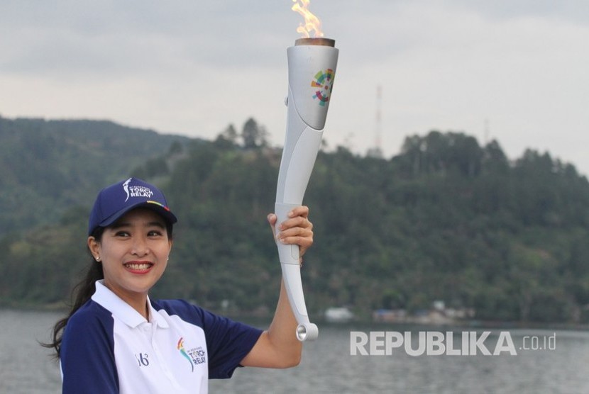 Artis Olivia Zalianty memegang obor Asian Games 2018 dengan latar belakang Danau Toba, di Parapat, Simalungun, Sumatera Utara, Rabu (1/8). 