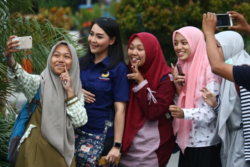 Artis Tessa Kaunang (kedua kiri) yang juga Calon Legislatif dari Partai Nasional Demokrat (Nasdem) berfoto bersama dengan warga disela pembagian selebaran berisi ajakan untuk menghormati guru di Surabaya, Jawa Timur, Ahad (17/2/2019).