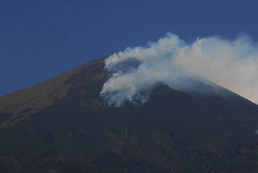 Asap mengepul dari kebakaran hutan di Gunung Sindoro terlihat dari Desa Tegalrejo, Ngadirejo, Temanggung, Jawa Tengah, Minggu (9/9). 