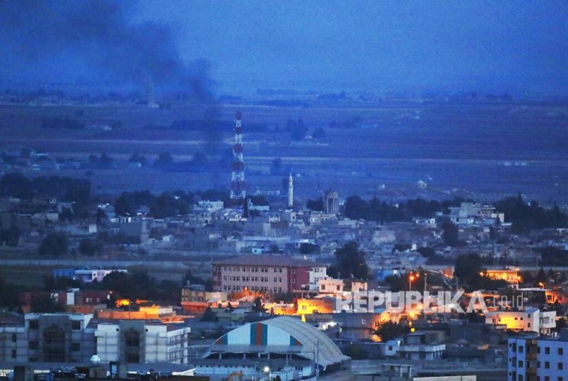 Asap mengepul di kejauhan akibat roket yang ditembakkan Turki ke arah Ras al-Ayn, Suriah, Selasa, (15/10) (Lefteris Pitarakis/AP)