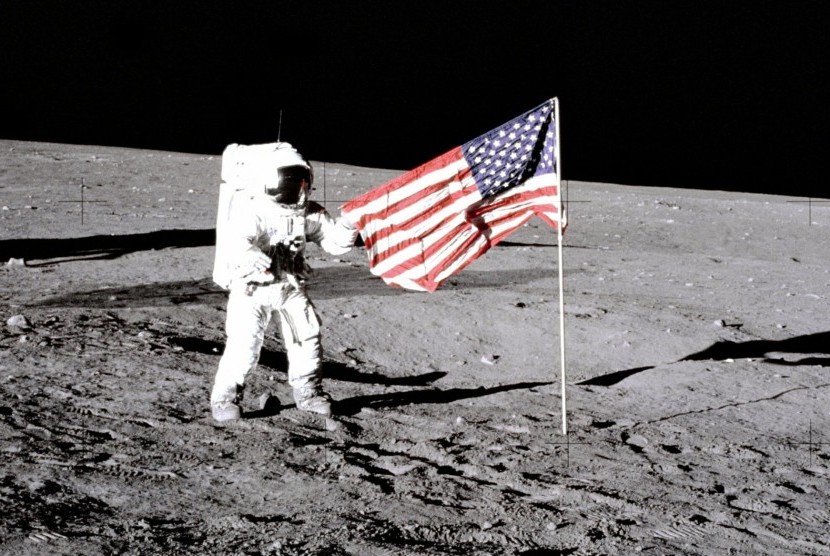 Astronaut Charles Conrad Jr berdiri di samping bendera AS dalam misi menggunakan Apollo 12 pada 14 November 1969.
