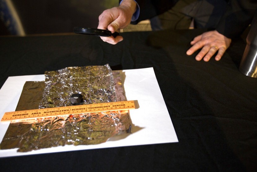 Astronomer Todd Slisher mengobservasi sepotong meteorit saat konferensi pers di Longway Planetarium di Flint, Michigan, Jumat (19/1).