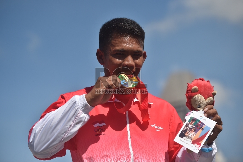 Atlet dayung putra Indonesia Marjuki menggigit medali emas ketika prosesi penyerahan medali setelah finish pertama final kano nomor C1 1000 meter putra SEA Games ke-28 di Teluk Marina, Singapura, Sabtu (6/6). (Antara Foto/Wahyu Putro)