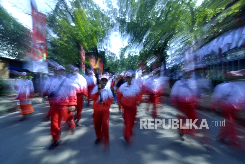 Atlet difabel Legendaris Tenis Meja Abdul Kholiq membawa api obor saat Kirab Api Pekan Paralimpik Nasional (Peparnas) XV 2016 di Jalan Diponogoro, Kota Bandung, Sabtu (15/10).