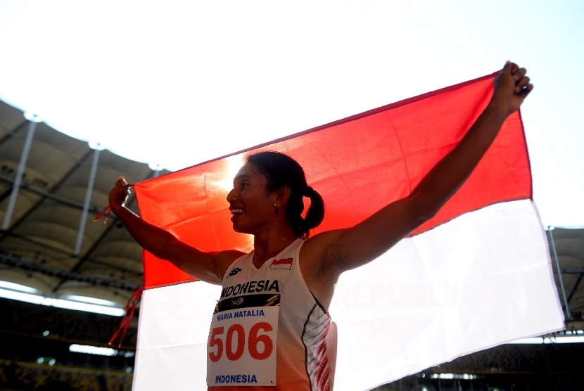 Atlet Indonesia Maria Natalia Londa membawa bendera merah putih usai mendapatkan perak pada nomor Lompat Jangkit SEA Games 2017 Kuala Lumpur di Stadion Bukit Jalil, Malaysia, Rabu (23/8). 