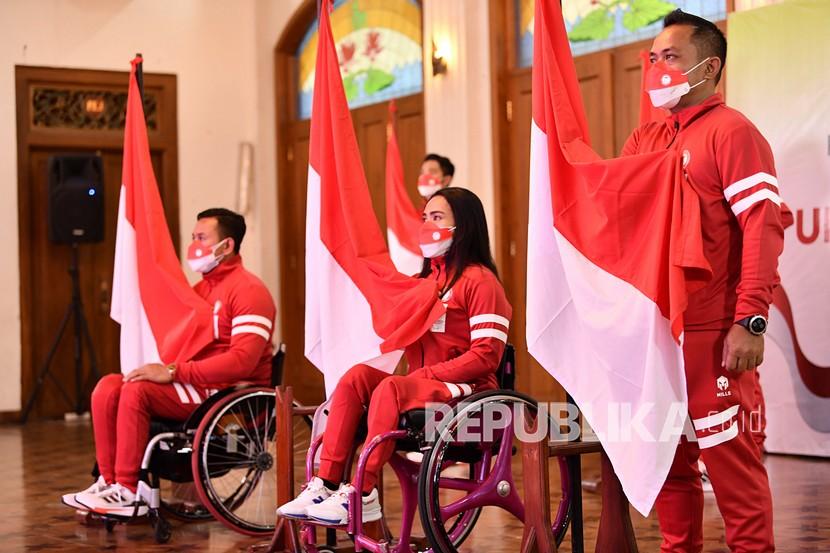 Atlet National Paralympic Committee (NPC) balap kursi roda Zaenal Arifin (kiri), angkat berat Ni Nengah Widiasih (tengah), dan menembak Bolo Triyanto (kanan) memegang bendera saat acara Pengukuhan dan Pelepasan Atlet NPC di Hotel Kusuma Sahid, Solo, Jawa Tengah, Sabtu (14/8/2021). NPC Indonesia memberangkatkan 23 atlet dari tujuh cabang olahraga pada pesta olahraga penyandang disabilitas dunia Paralimpiade Tokyo 2020. 