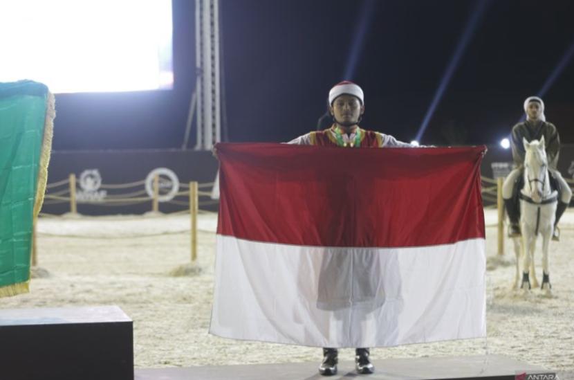 Atlet panahan berkuda Indonesia Muhammad Yahya Ayyash membentangkan bendera merah putih setelah penobatan gelar juara ketiga nomor qabaq pada Piala Dunia Panahan Berkuda 2023 di Al-Ula, Arab Saudi, Senin (18/12/2023).