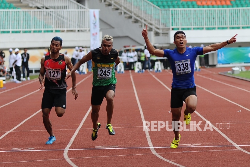 Atlet Sumatra Barat Yaspi Boby (kanan) mengangkat tangan saat memenangkan lari 100 meter putra di Stadion Pakansari, Cibinong, Jawa Barat, Kamis (22/9). 