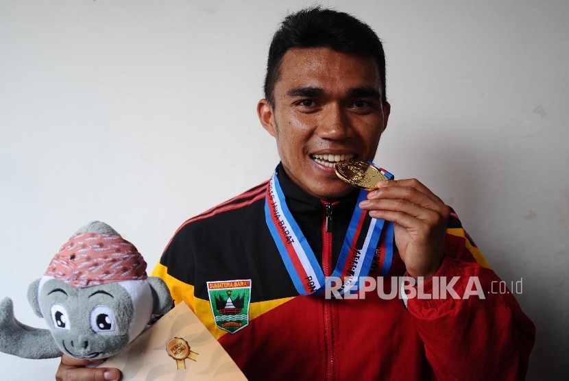 Atlet Sumatra Barat, Yaspi Boby mengigit medali usai penyerahan medali lari nomor 100 meter putra di stadion Pakansari, Cibinong, Jawa Barat, Kamis (22/9).