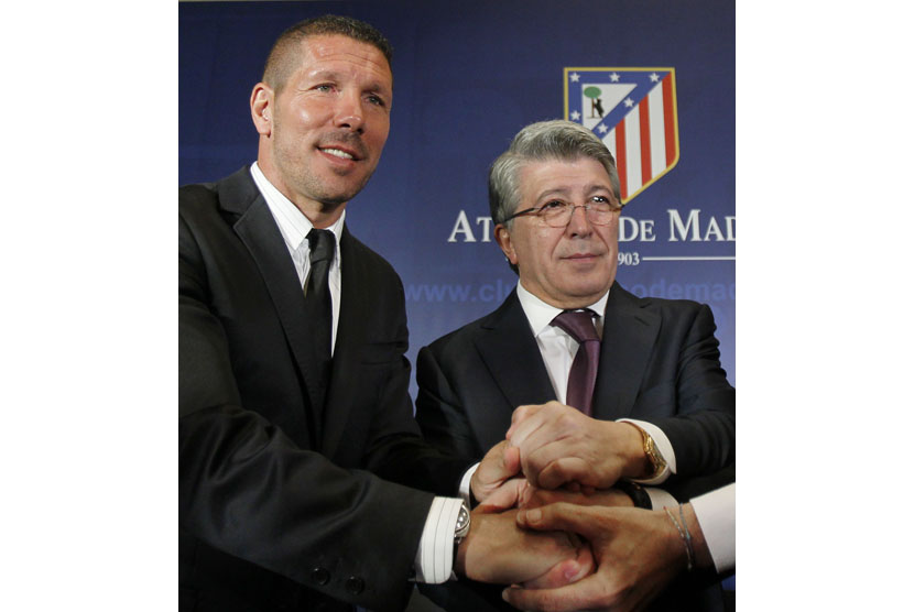 Atletico de Madrid's new soccer coach Diego 'Cholo' Simeone from Argentina, left, shakes hands with club president Enrique Cerezo, right, during his official presentation at the Vicente Calderon stadium in Madrid, Spain, Tuesday, Dec. 27, 2011.