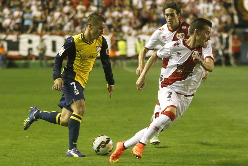 Atletico Madrid's Antoine Griezmann (L) and Rayo Vallecano's Roberto Triguero and Jose Baena (C) challenge for the ball during their Spanish first division soccer match at at Vallecas stadium in Madrid August 25, 2014