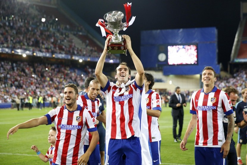 Atletico Madrid's Diego Godin (C), Koke (L) and Mario Mandzukic celebrate with the trophy after they won the Spanish Super Cup against Real Madrid at the Vicente Calderon stadium in Madrid August 23, 2014.