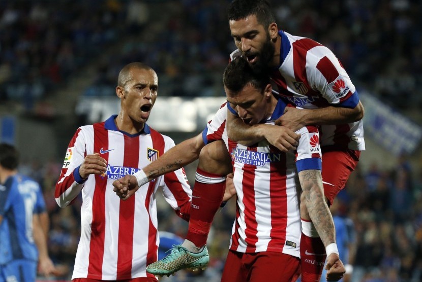 Atletico Madrid's Mario Mandzukic celebrates with teammates Arda Turan (R) and Joao Miranda (L) after scoring a goal against Getafe next to teammate Arda Turan during their Spanish first division soccer match at Coliseum Alfonso Perez stadium in Getafe, ne