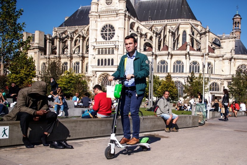 Pria naik skuter listrik di jalanan kota Paris, Prancis. Utilitas Prancis EDF melihat output listriknya turun ke level terendah dalam 30 tahun.