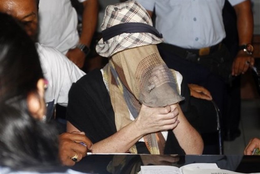 Australian Schapelle Corby, covering her face, gestures at the correctional office after she received her parole in Bali, Indonesia, Monday, Feb. 10, 2014.  