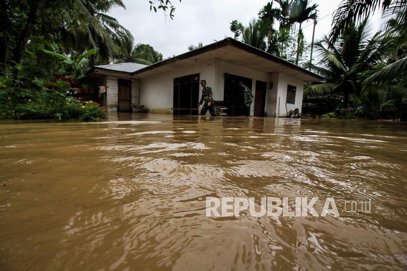 Babinsa TNI Kodim 0103 Aceh Utara mengecek rumah warga saat terjadi bencana banjir di Desa Hasan Kareung, Blang Mangat, Lhokseumawe, Aceh, Sabtu (5/12/2020). Data Badan Penanggulangan Bencana Daerah (BPBD) menyebutkan bencana banjir terus meluas, merendam 502 desa di 20 kecamatan di Aceh Utara, menyebabkan sekitar seribu warga mengungsi. 