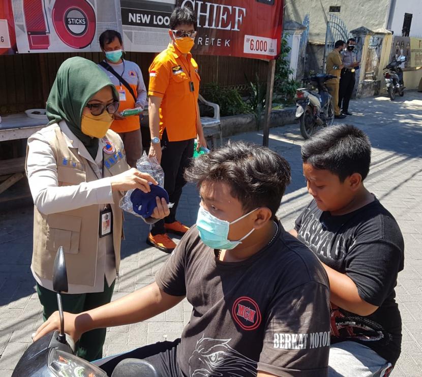 Direktur Pemulihan dan Peningkatan Sosial Ekonomi dan Sumber Daya Alam BNPB, Andi Eviana (kiri) membagikan masker kepada warga di Kota Surabaya, Senin (26/7). Pembagian masker tersebut merupakan salah satu upaya BNPB dalam mendukung optimalisasi Posko PPKM Mikro.