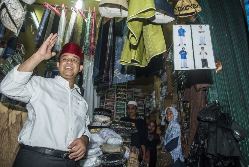 Bakal Calon Gubernur DKI Jakarta Anies Baswedan memberi salam saat membeli peci khas Betawi di Blok F Pasar Tanah Abang, Jakarta, Jumat (21/10). 