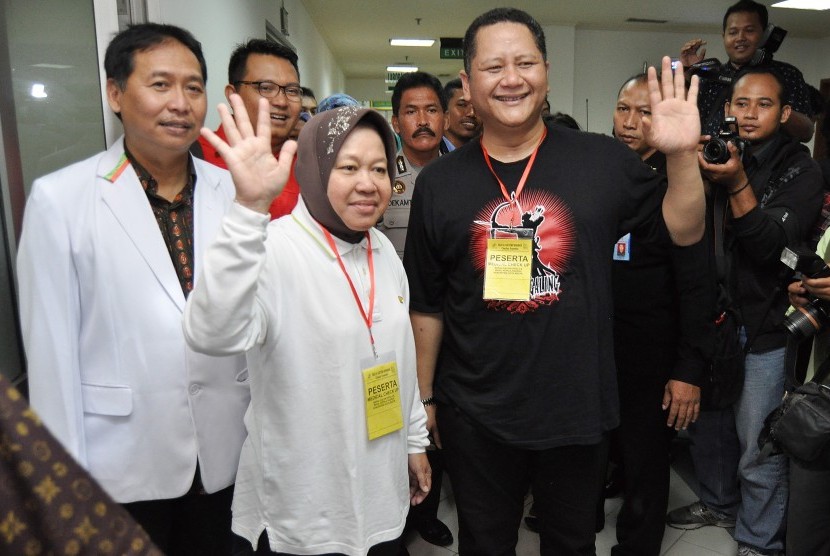 Bakal calon Wali Kota Surabaya Tri Rismaharini (kedua kiri) dan wakilnya Wisnu Sakti Buana (kanan) melambaikan tangan kepada wartawan seusai menjalani tes kesehatan di Graha Amerta, RSUD Dr. Soetomo, Surabaya, Jawa Timur, Selasa (28/7).