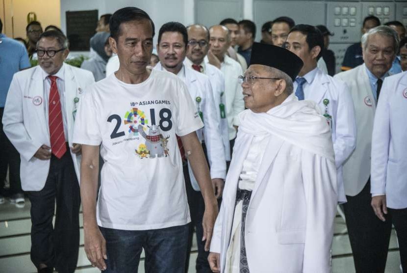 Incumbent President Joko Widodo (white t-shirt) talks to his running mate KH Ma'ruf Amin (black cap) after following medical check up at Gatot Subroto Army Hospital (RSPAD), Jakarta, Sunday (August 12). 