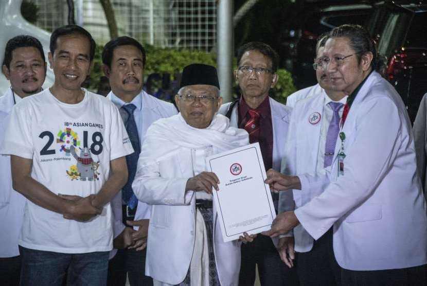 Bakal capres-cawapres Pilpres 2019, Joko Widodo (kedua kiri) menyaksikan Ma'ruf Amin (tengah) menerima dokumen dari Ketua Umum PB IDI Ilham Oetama Marsis (kanan) seusai menjalani tes kesehatan di RSPAD, Jakarta, Minggu (12/8).