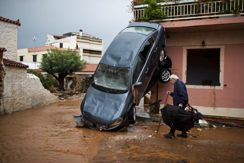 Banjir bandang di Mandra di barat Athena, Yunani menyebabkan mobil menimpa rumah, Kamis (16/11). 