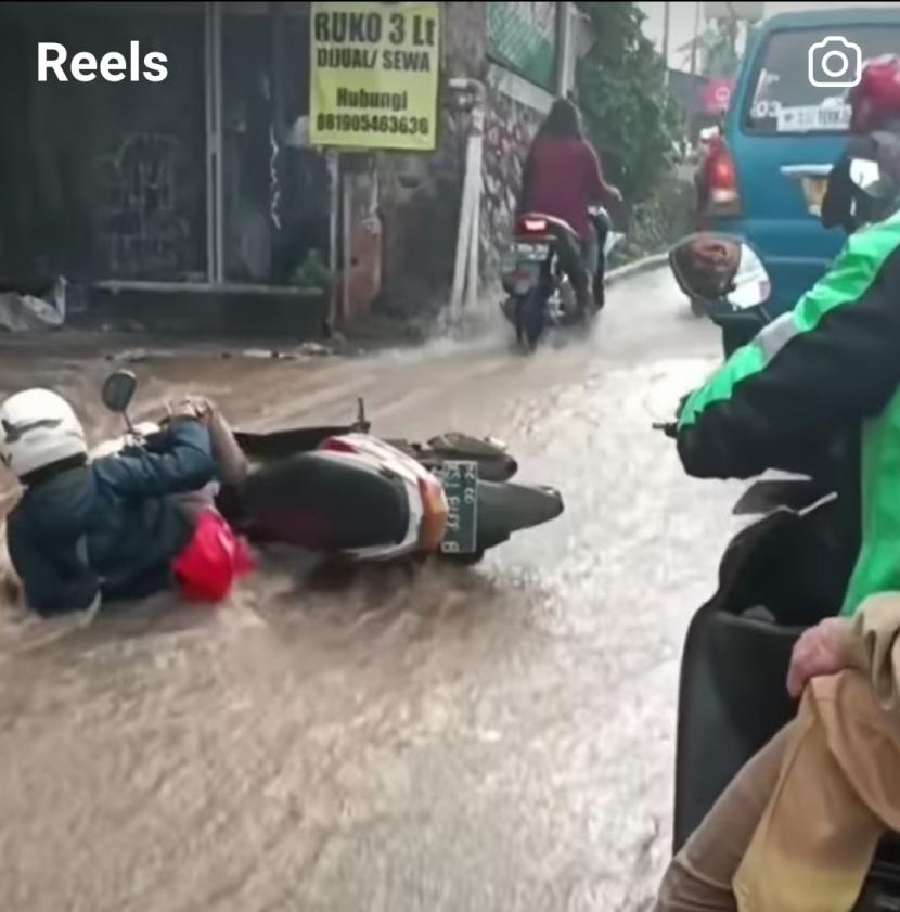 Banjir di Jalan Raya Sawangan, Depok membuat pengendara motor tergelincir dan jatuh, Senin (19/6/2023).
